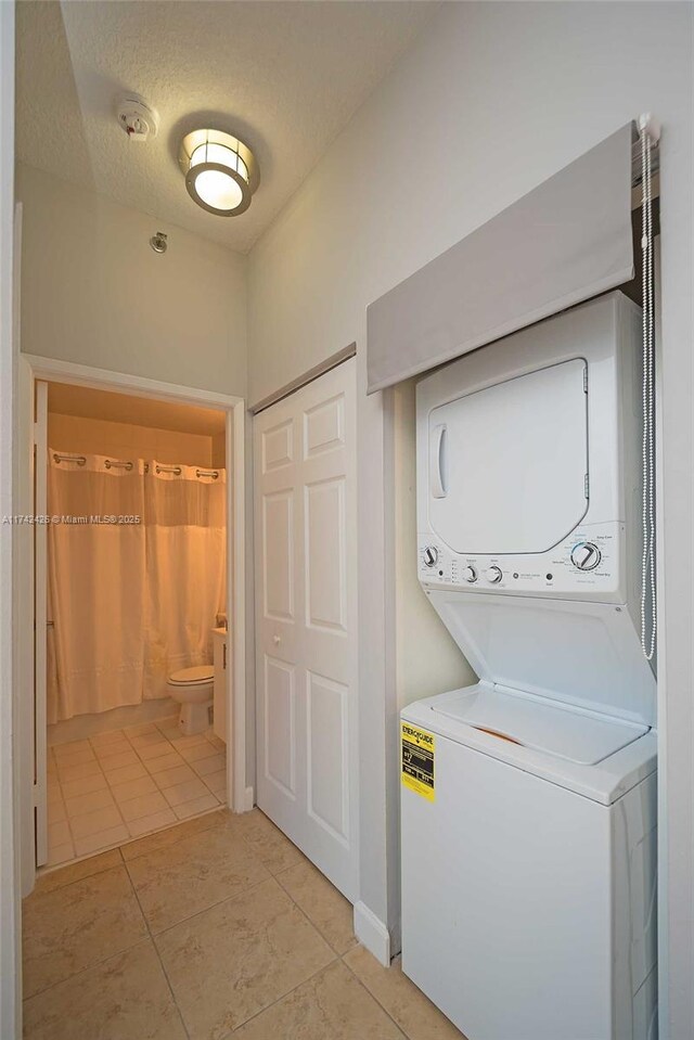 3300 NE 192nd St Unit 111, Aventura, FL 33180 - laundry area with stacked washer and clothes dryer, light tile patterned floors, and a textured ceiling