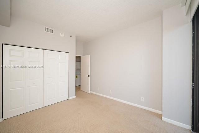 3300 NE 192nd St Unit 111, Aventura, FL 33180 - unfurnished bedroom featuring light colored carpet, a closet, and baseboards