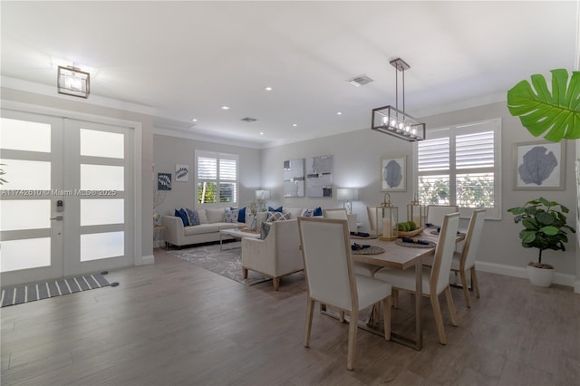 dining space featuring hardwood / wood-style flooring, crown molding, and french doors