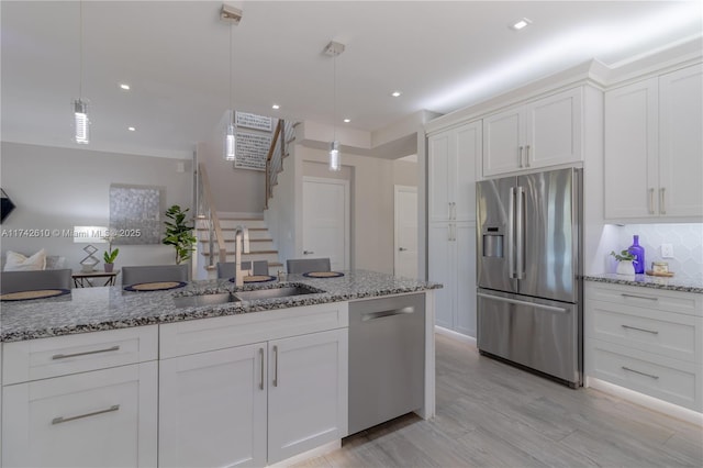 kitchen with white cabinetry, stainless steel appliances, sink, and pendant lighting