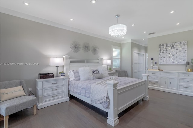 bedroom featuring a notable chandelier, crown molding, dark wood-type flooring, and ensuite bathroom