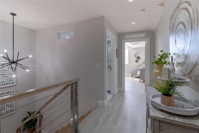 corridor with an inviting chandelier and light hardwood / wood-style floors