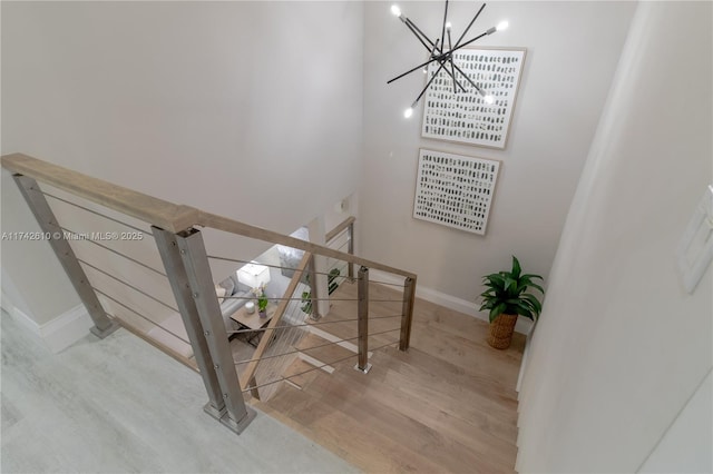 stairway featuring hardwood / wood-style flooring and an inviting chandelier