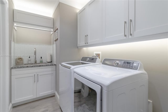 clothes washing area with cabinets, separate washer and dryer, and sink