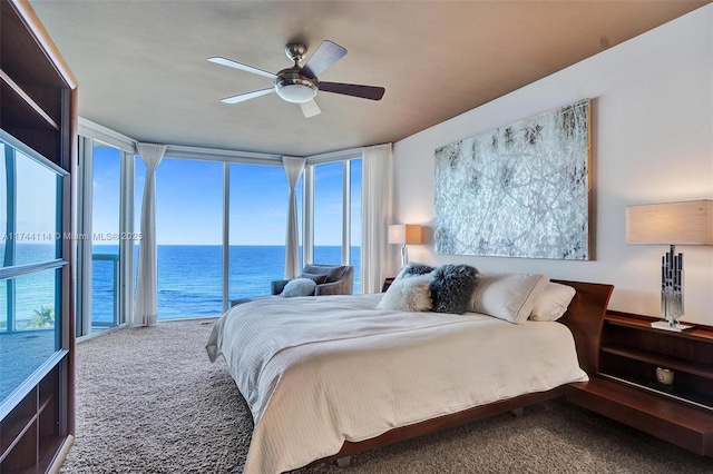 carpeted bedroom with expansive windows, a water view, access to outside, and ceiling fan