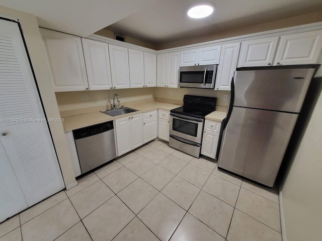 kitchen featuring stainless steel appliances, light tile patterned flooring, sink, and white cabinets