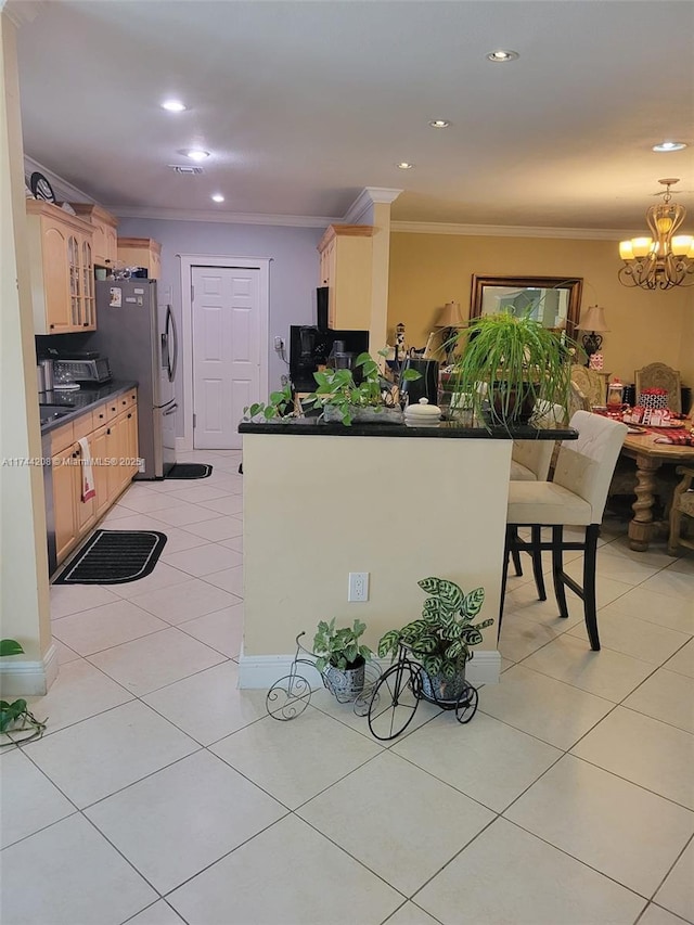 kitchen featuring light tile patterned floors, stainless steel fridge, ornamental molding, kitchen peninsula, and a chandelier