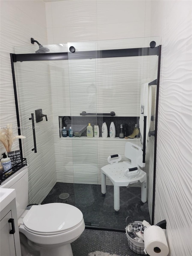 bathroom with vanity, tiled shower, and toilet