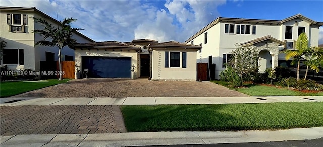 view of front facade with stucco siding, an attached garage, decorative driveway, and fence