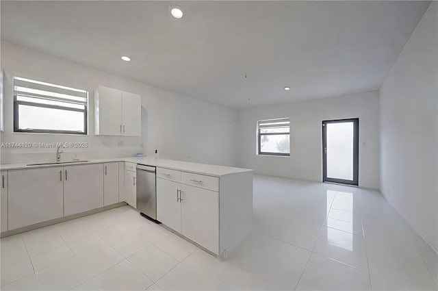 kitchen featuring dishwasher, light countertops, a peninsula, and a sink