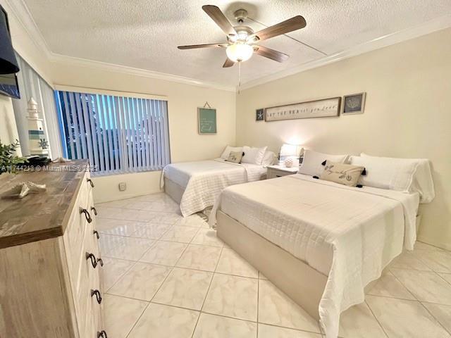 bedroom featuring ceiling fan, ornamental molding, a textured ceiling, and light tile patterned floors