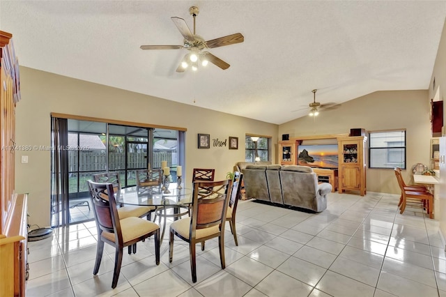 tiled dining room with ceiling fan, lofted ceiling, a textured ceiling, and a wealth of natural light