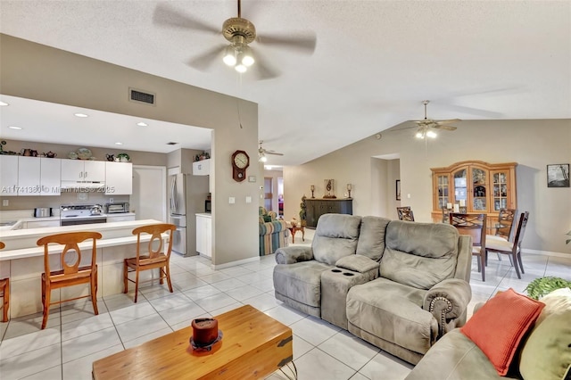 living room featuring light tile patterned flooring, ceiling fan, lofted ceiling, and a textured ceiling