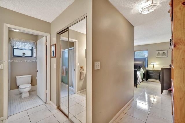 hall with light tile patterned floors and a textured ceiling