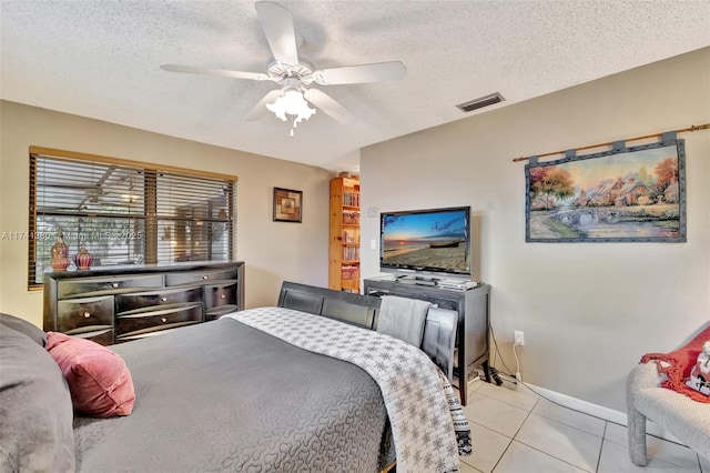 tiled bedroom with ceiling fan and a textured ceiling