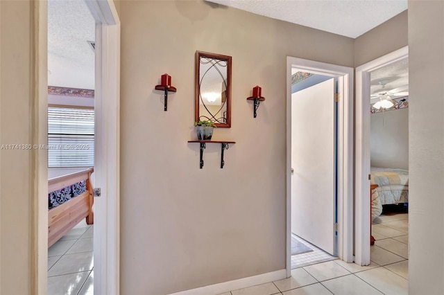 corridor featuring a textured ceiling and light tile patterned flooring