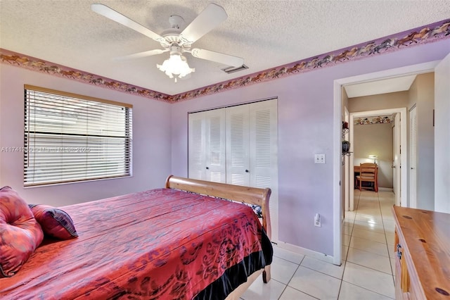 tiled bedroom with ceiling fan, a closet, and a textured ceiling