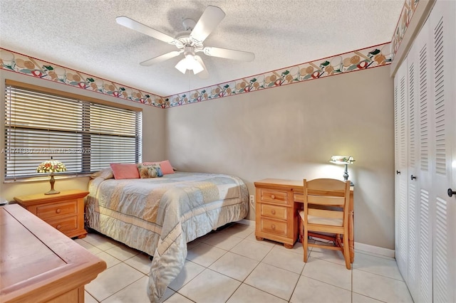 bedroom with ceiling fan, a closet, a textured ceiling, and light tile patterned flooring