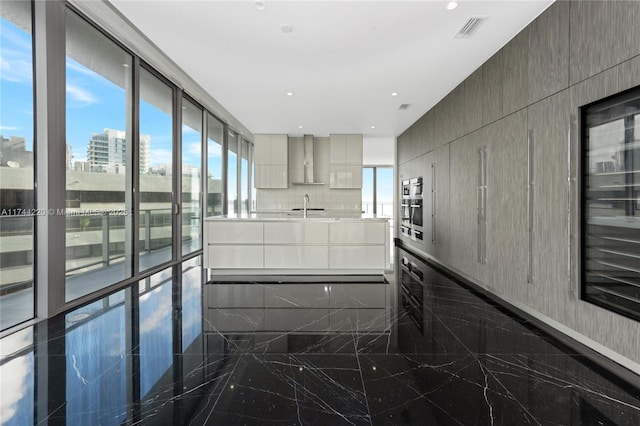 kitchen with sink, wall chimney range hood, oven, and decorative backsplash