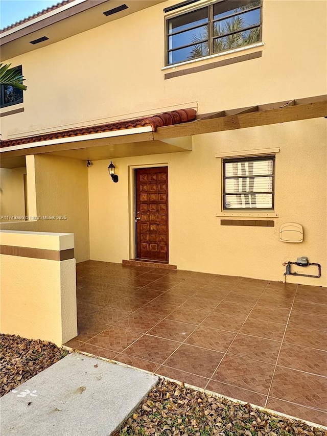 entrance to property with a tiled roof and stucco siding