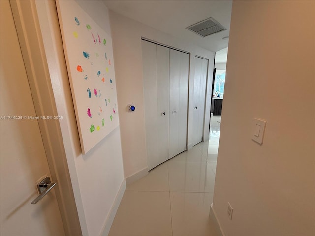 hallway featuring visible vents, baseboards, and light tile patterned flooring