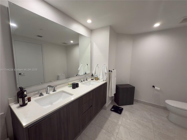 bathroom with recessed lighting, a sink, toilet, and double vanity