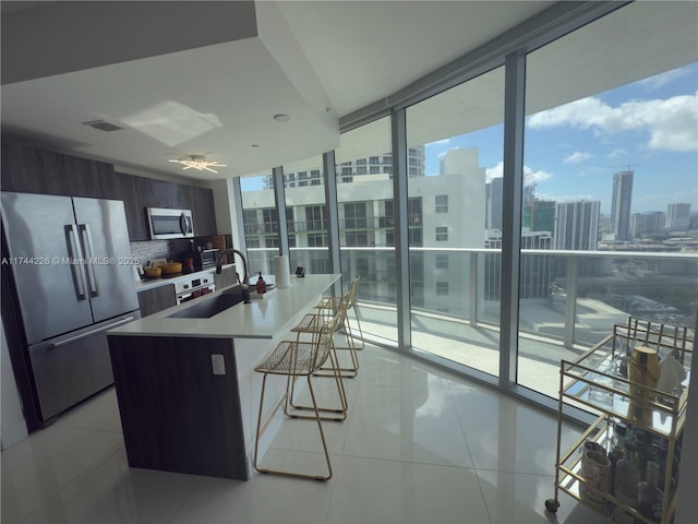 kitchen with a city view, stainless steel appliances, a sink, expansive windows, and modern cabinets