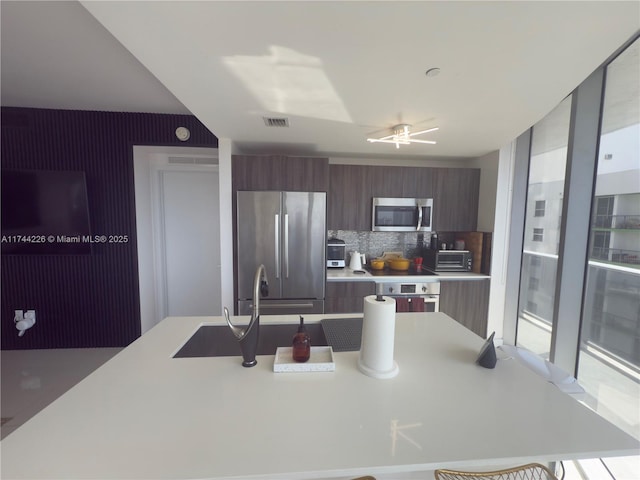 kitchen featuring stainless steel appliances, modern cabinets, light countertops, and visible vents