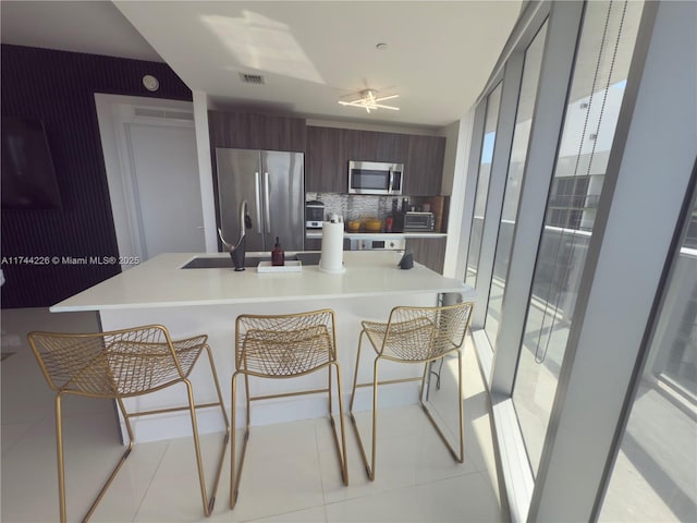 kitchen featuring light countertops, appliances with stainless steel finishes, modern cabinets, and visible vents