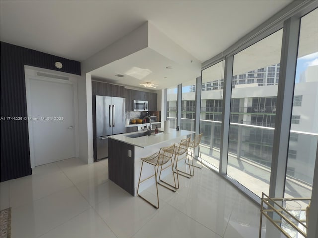 kitchen with tasteful backsplash, light countertops, appliances with stainless steel finishes, modern cabinets, and a kitchen breakfast bar