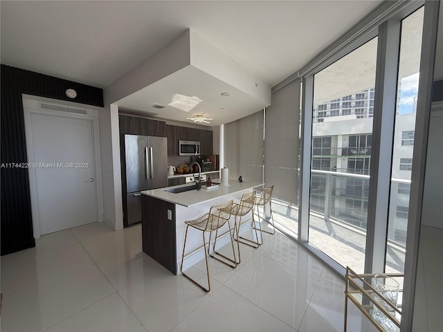 kitchen featuring stainless steel appliances, a healthy amount of sunlight, a kitchen bar, and modern cabinets