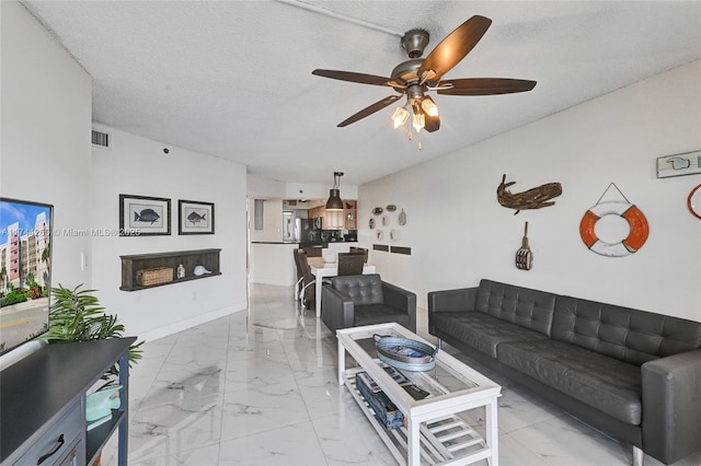 living room with ceiling fan and a textured ceiling