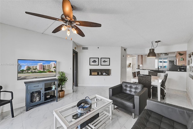 living room featuring ceiling fan and a textured ceiling