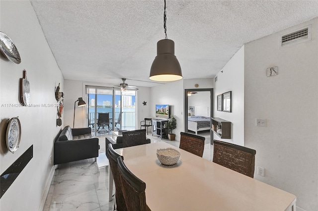 dining space featuring ceiling fan and a textured ceiling