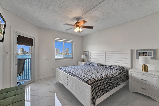 bedroom featuring ceiling fan, access to exterior, and a textured ceiling