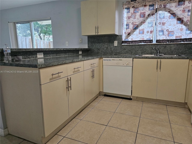 kitchen with light tile patterned flooring, sink, dark stone countertops, white dishwasher, and backsplash