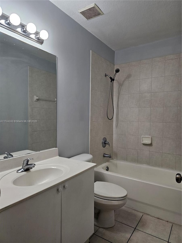 full bathroom featuring toilet, a textured ceiling, vanity, tiled shower / bath combo, and tile patterned flooring