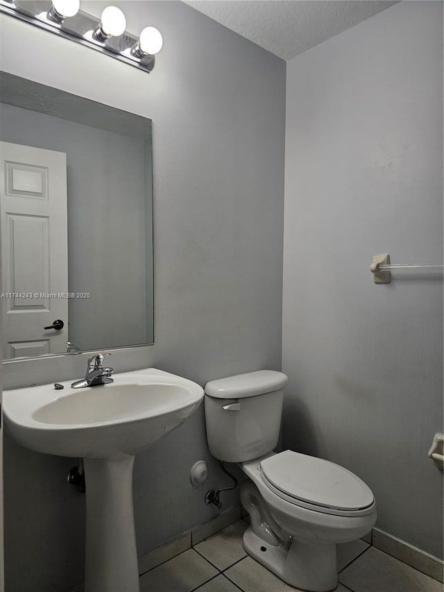 bathroom with a textured ceiling, tile patterned floors, and toilet