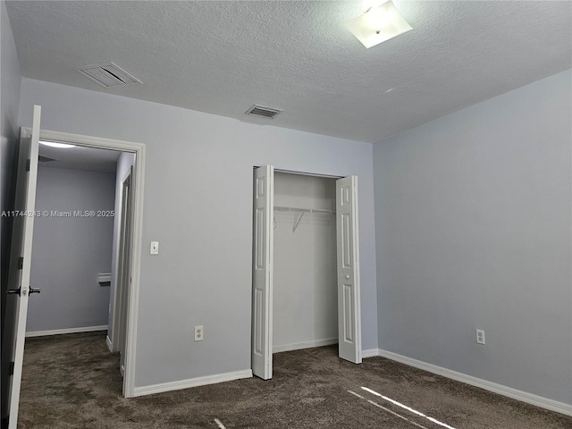 unfurnished bedroom featuring dark colored carpet, a textured ceiling, and a closet