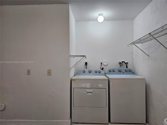 clothes washing area with separate washer and dryer and a textured ceiling