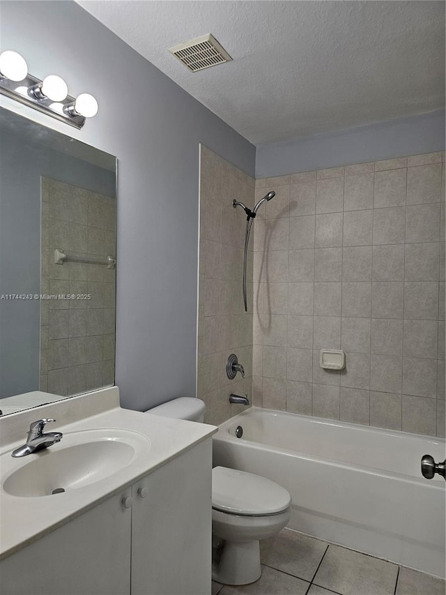 full bathroom with tiled shower / bath, tile patterned flooring, vanity, toilet, and a textured ceiling