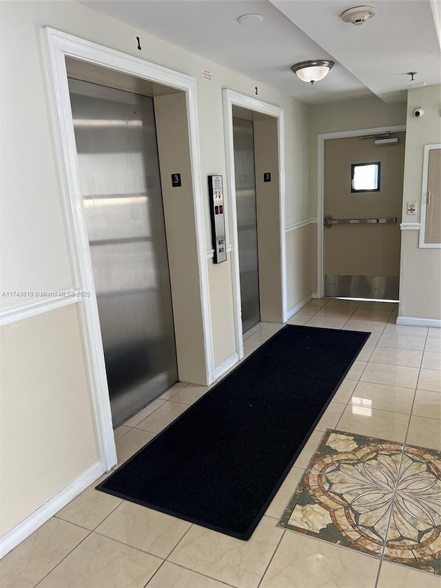 corridor with elevator and light tile patterned floors