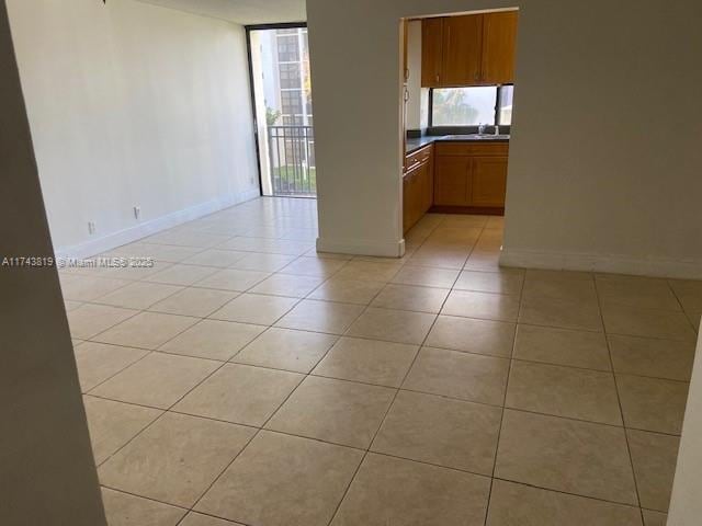 unfurnished room with light tile patterned flooring, sink, and a wall of windows