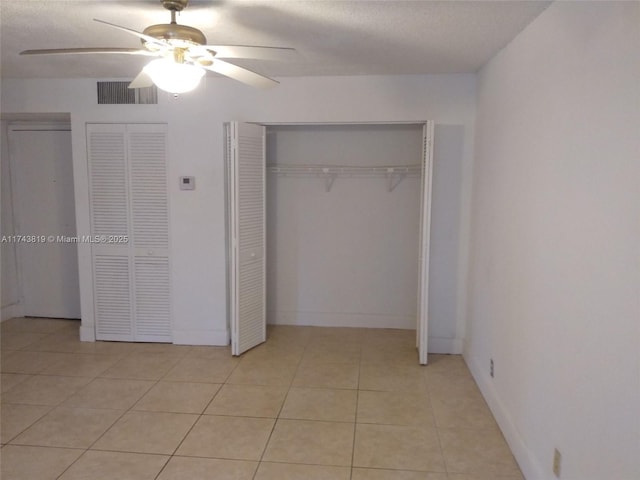 unfurnished bedroom with ceiling fan, a textured ceiling, and light tile patterned floors