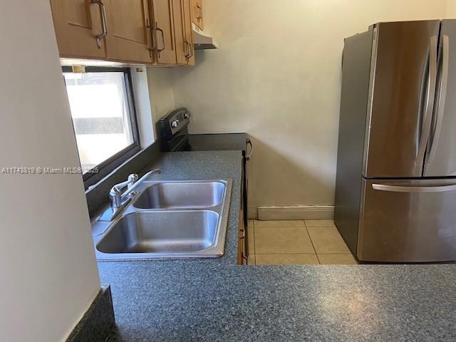 kitchen featuring light tile patterned floors, stainless steel fridge, sink, and electric range