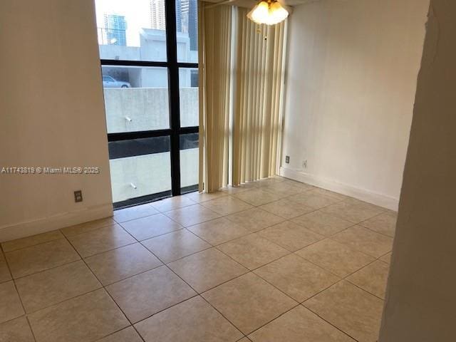 spare room with light tile patterned floors and a wall of windows