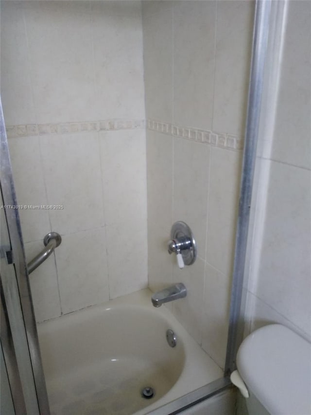 bathroom featuring tiled shower / bath combo and toilet