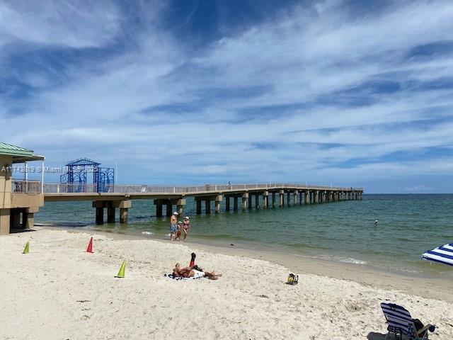 view of dock with a beach view and a water view