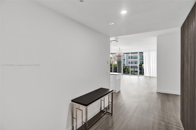 hallway featuring expansive windows, wood-type flooring, and an inviting chandelier