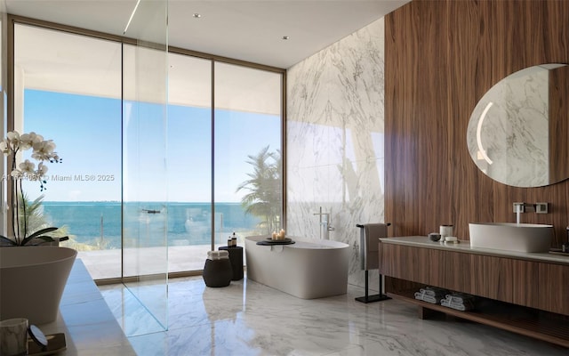 bathroom featuring a tub to relax in, expansive windows, vanity, and a water view